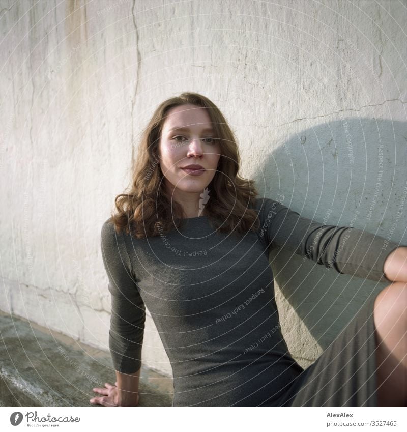 analoges Portrait einer jungen Frau im Kleid vor einer Wand Mädchen schön groß sportlich schlank fit brünett Locken langes Haar Beton Sand Strand Abend Körnung