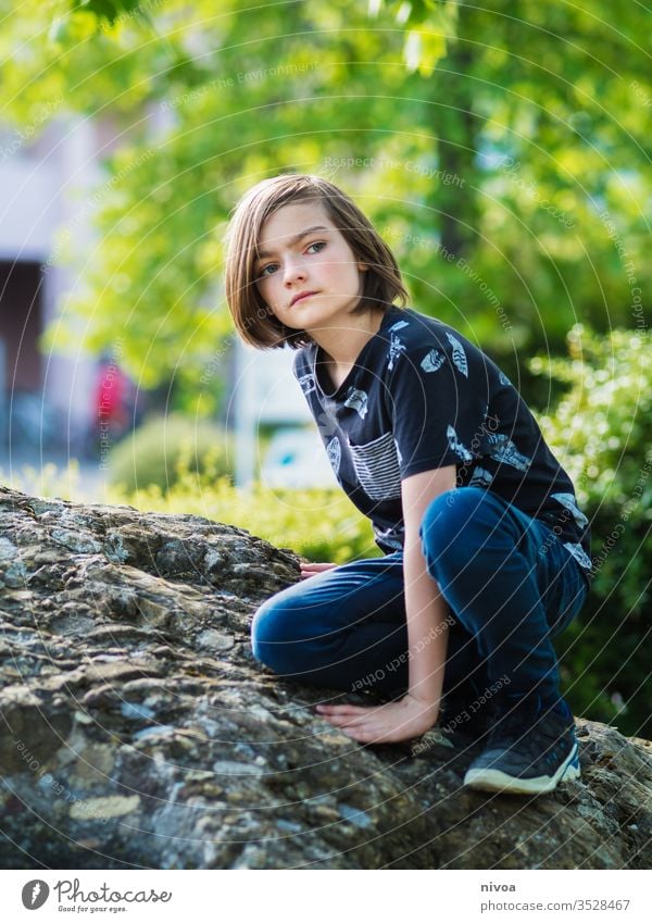 Junge sitzt auf einem Felsen Klettern aussruhen Sommer T-Shirt Kind blond Freude Farbfoto Natur Gras Tag grün Außenaufnahme jung Park Garten sonnig Kindheit