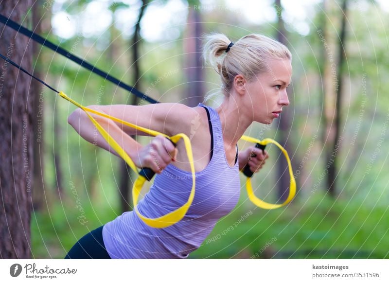 Training mit Fitnessgurten im Freien. Sport trx Natur Übung schön Kaukasier jung Gesundheit Gerät Frau Körper Suspension passen Park sportlich Trainerin Baum