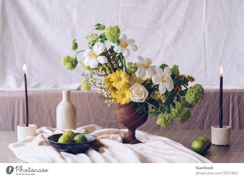 Stilleben mit einem schönen Blumen-, Kerzen- und Lindenstrauss Tisch Vase Hochzeit Blumenstrauß Dekoration & Verzierung weiß Hintergrund Innenbereich Kalk