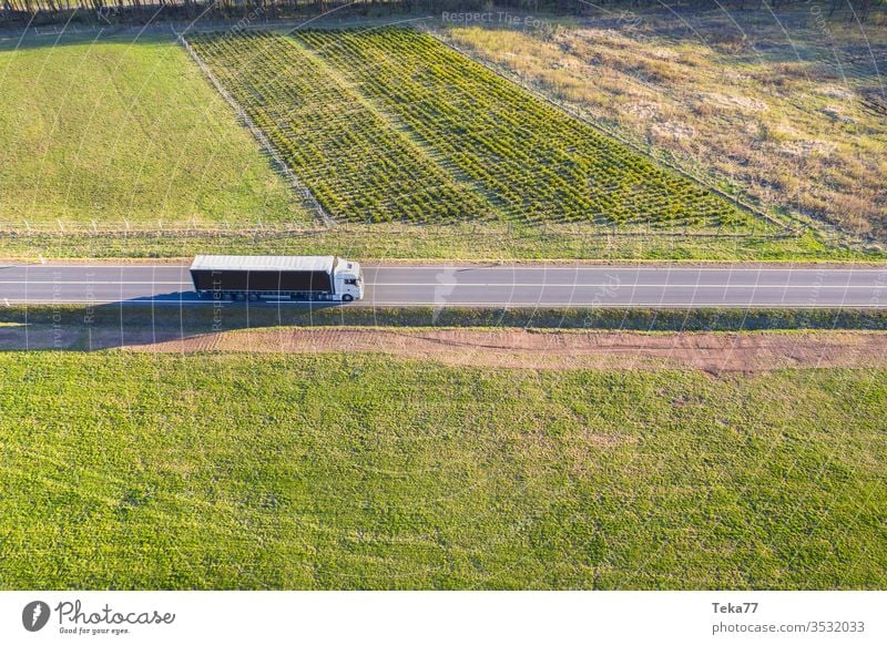 ein Lastwagen von oben in einer Frühlingswiesenlandschaft Straße Straße von oben Straße mit einem Auto Autofahren Auto von oben landwirtschaftlich