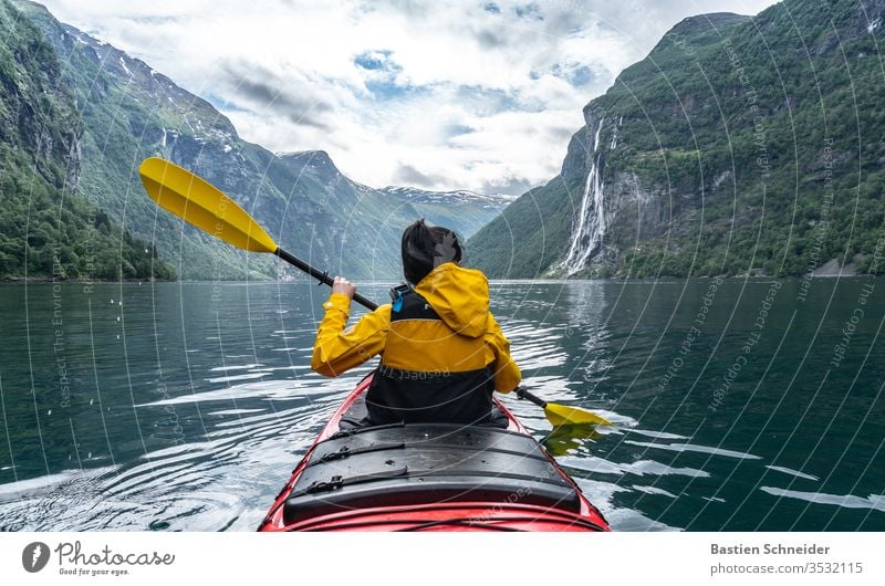 Frau paddelt im Geirangerfjord, Norwegen Berge u. Gebirge Landschaft Fjord Umwelt Farbfoto Wasserfall Schönes Wetter Sonnenlicht Wolken Außenaufnahme