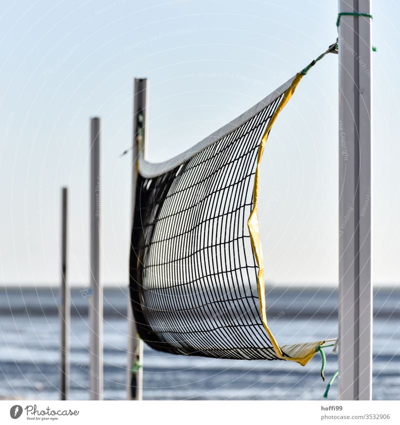 Der Wind spielt mit dem Volleyballnetzt am Strand - keiner da. Volleyballfeld Sport Beachvolleyball Sommer Sport Sand Netz Spielen Menschenleer Ballsport blau