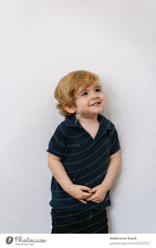 Glückliches kleines Kind steht in einer Weile in der Wand wenig Junge Energie Vorschule bezaubernd Freude Lachen Spaß Kindheit expressiv spielerisch Lächeln