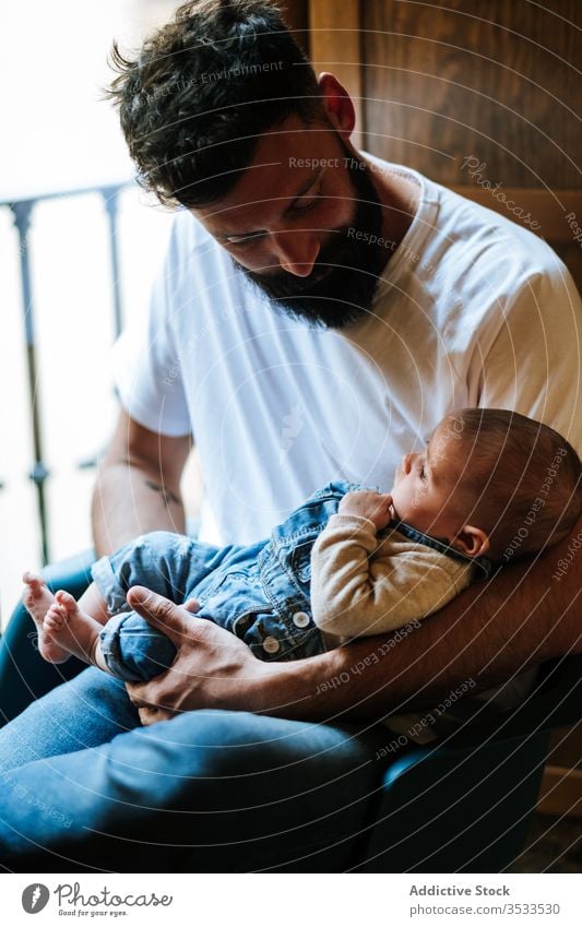 Bärtiger Vater mit Baby am Fenster sitzend Vollbart Kommunizieren Umarmung heimwärts Liebe Angebot gemütlich Stuhl Mann Säugling Kind wenig Umarmen Eltern