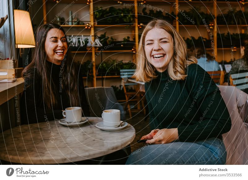 Freundinnen ruhen sich in gemütlichem Cafe aus Frauen Café Lachen Zusammensein Kaffee Smartphone benutzend Witz lässig Wochenende jung Sitzung Restaurant