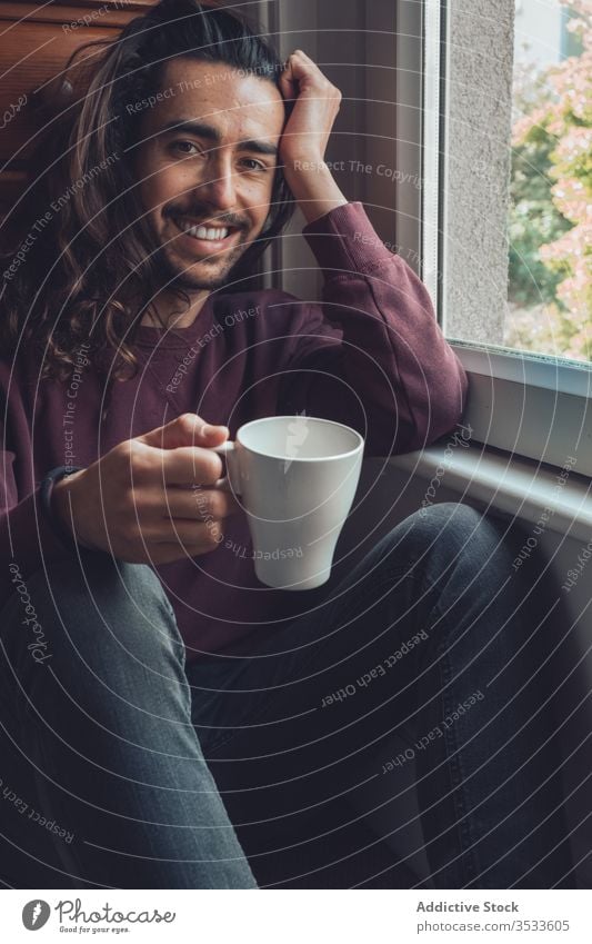 Erwachsener Mann mit Becher, der aus dem Fenster schaut trinken zu Hause bleiben ruhen heimwärts Coronavirus covid-19 Morgen gemütlich heiß lässig männlich