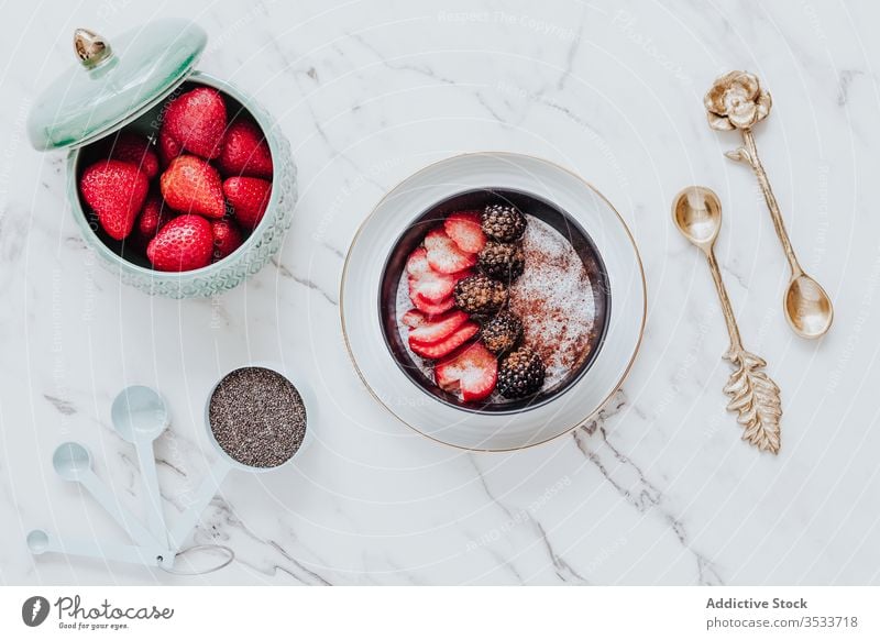 Köstliches Dessert mit frischen Beeren mit Zimt im Arrangement mit dekorativen goldenen Löffeln auf dem Tisch Frühstück Joghurt Schalen & Schüsseln Brombeeren