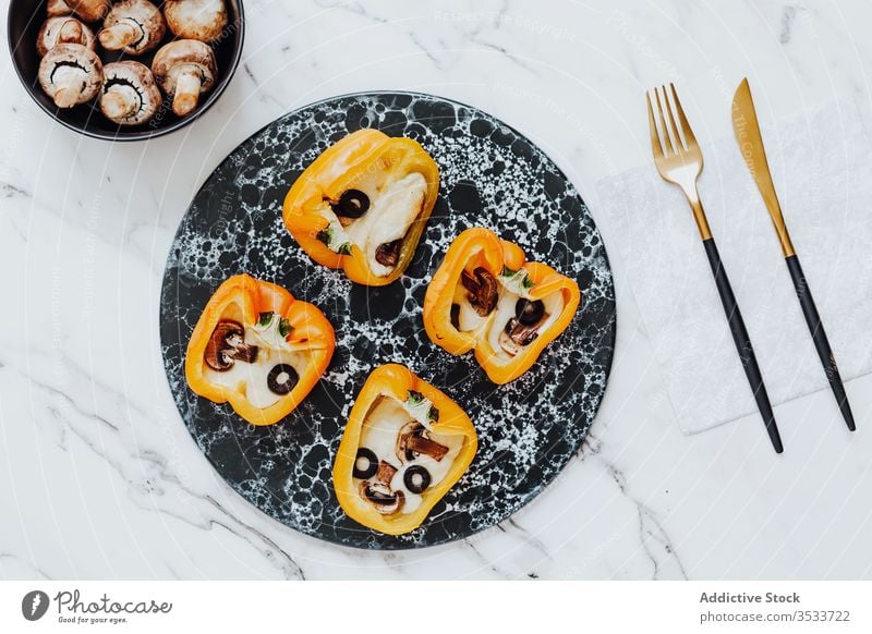 Paprika gefüllt mit gebratenen Champignons und Käse mit Oliven auf Marmorplatte Pilz oliv Lebensmittel Snack Schalen & Schüsseln Messer Gabel Mahlzeit Teller