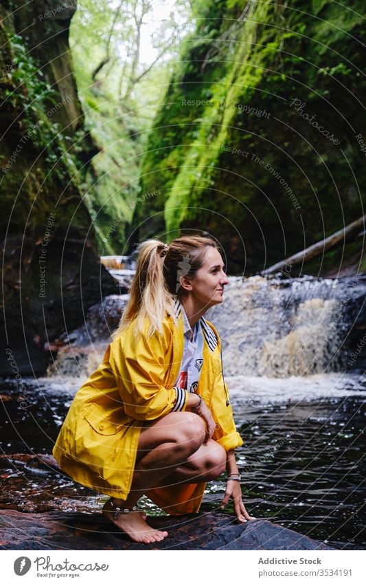 Fröhliche Touristin kauert in der Nähe von Wasserfall und grünem Berg Berge u. Gebirge Natur erkunden Glück Frau hocken idyllisch Fernweh Paradies Urlaub