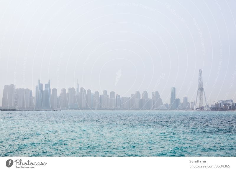 Atemberaubende Aussicht auf die Wolkenkratzer in Dubai im Morgengrauen. VEREINIGTE ARABISCHE EMIRATE Wellenbrecher Steine MEER Strand Blauer Himmel Landschaft