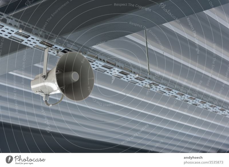 Ein grauer Sprecher hängt von der modernen Decke ab abstrakt wach ankündigen Ankündigung Architektur Kunst Audio Hintergrund Ausstrahlung Gebäude