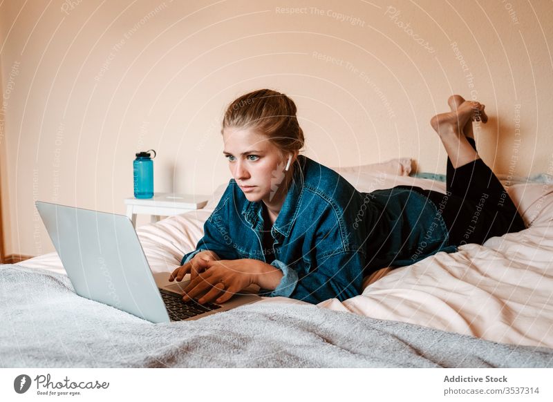 Frau schaut Film auf Laptop im gemütlichen Schlafzimmer heimwärts benutzend Bett liegend zuschauen Surfen soziale Netzwerke zuhören Interesse Filmmaterial