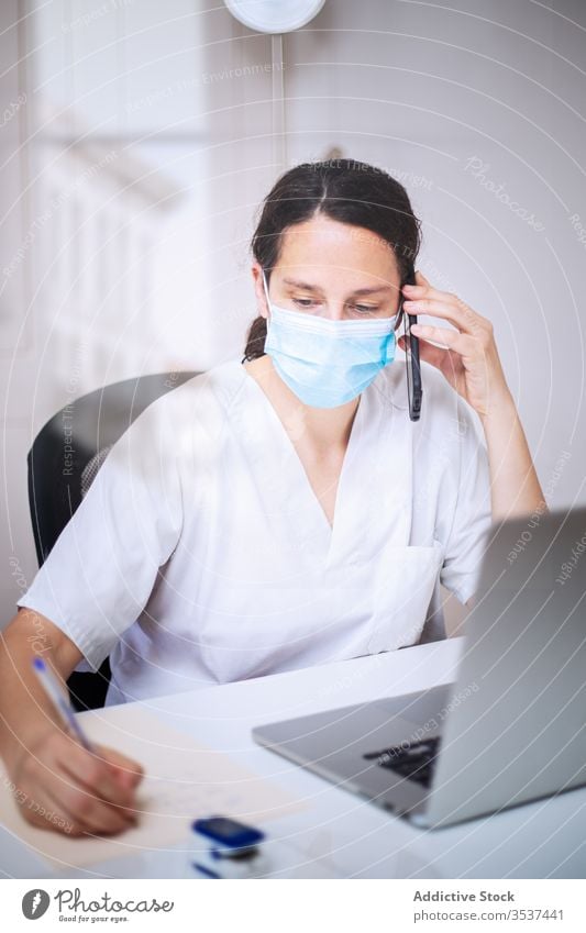 Junge Ärztin mit medizinischer Maske arbeitet am Laptop in der Klinik Frau Arzt Uniform Mundschutz Handschuh Schreibtisch ernst Krankenhaus professionell