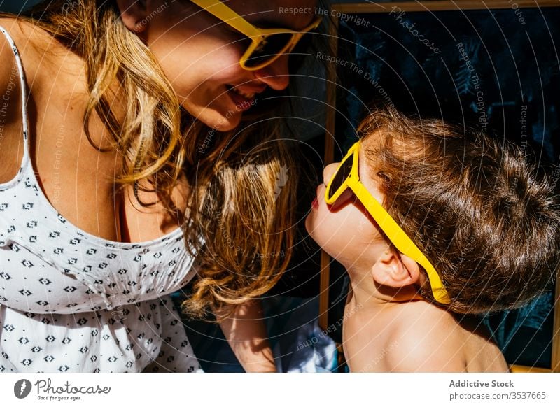 Positive Mutter spielt mit Sohn mit gelber Sonnenbrille an sonnigem Tag heimwärts Strand Liebe träumen Zusammensein Quarantäne Selbstisolierung