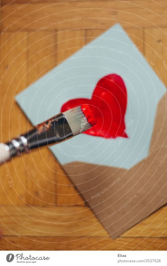 Ein Pinsel der mit roter Farbe ein Herz auf einen Brief malt Briefumschlag Liebesbrief malen Muttertag künstlerisch Malerei Emotionen Gefühle Post Valentinstag