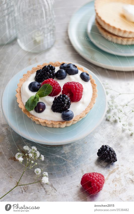 Törtchen mit Beeren auf einem kleinen türkisen Teller gebacken Dessert Farbfoto Backwaren Foodfotografie Blaubeeren Lebensmittel Himbeeren Kuchen lecker