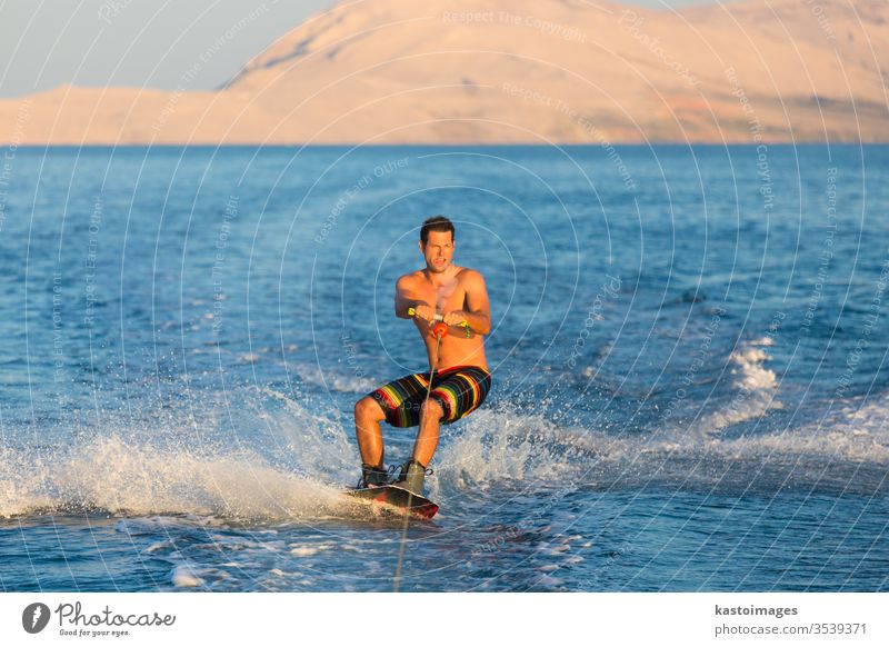 Wakeboarder im Sonnenuntergang. Sport Mann extrem Wakesurfing MEER winken Kabel Spaß Wasser Erholung platschen jung männlich Holzplatte Aktion Sommer Person