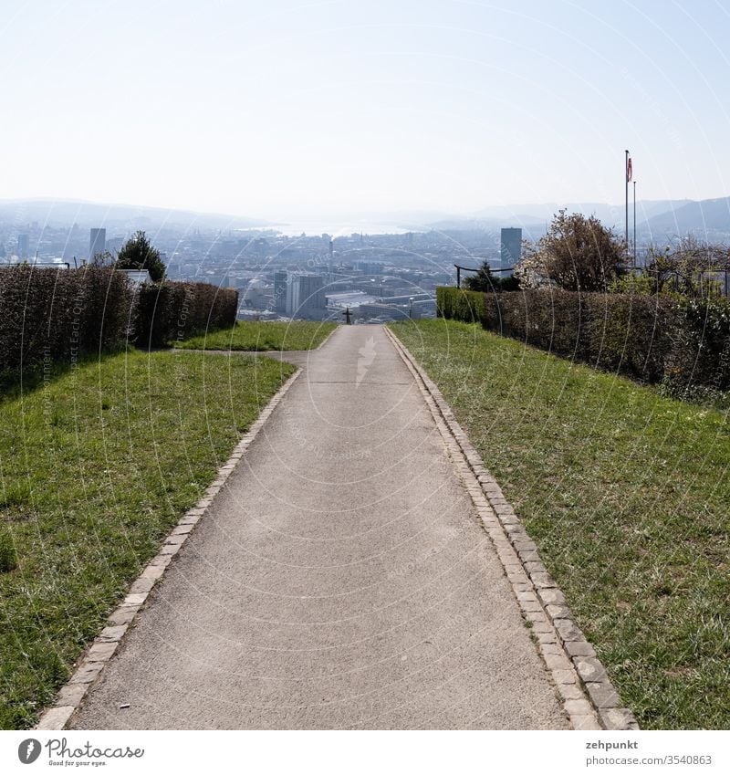 Blick einen Fussweg entlang auf Zürich, im Dunst verschwindet der Zürichsee Weg Kleingartenanlage Zentralperspektive Waidberg Schweiz Außenaufnahme Farbfoto