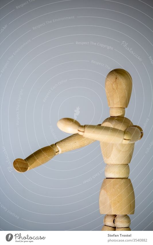 Holzstatue vor einem grauen Hintergrund Porträt Puppe Körper Konzept Holzarbeiten Pose Kunstturnen Marionette Design Model Spielzeug gelb Figur Single Aktion