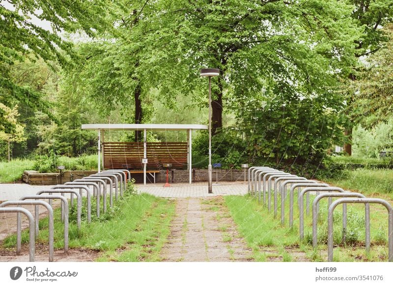 leere Fahrradständer im Hof umringt von üppigem Grün grün "Fahrradständer Fahrradhalter Fahrradparkplatz Radständer Parkplatz parkraum stellplatz fahrradständer