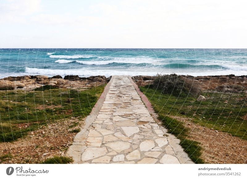 Im Vordergrund ein Betonweg, der einen Kiesel- und Steinstrand durchquert. selektiver Fokus. Meer Laufsteg MEER Himmel schön Tourismus reisen blau Landschaft