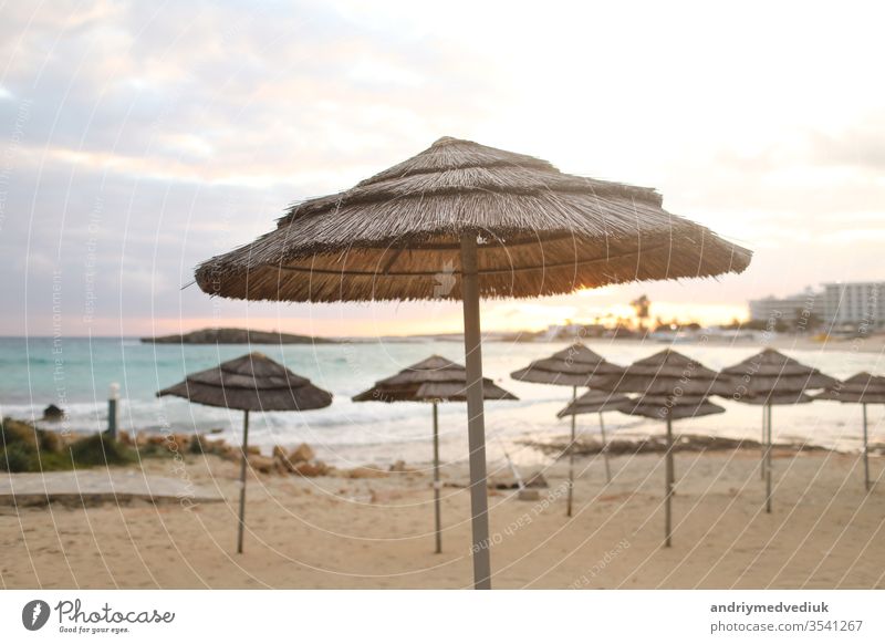 schöne Strohschirme am Strand am leeren Strand,,strahlend blaues Wasser und blauer Himmel,,paradiesischer tropischer Strand,,entspannende Zeit,,erstaunliche Aussicht,,keine Menschen,,Sonnenuntergang Hintergrund. selektiver Fokus