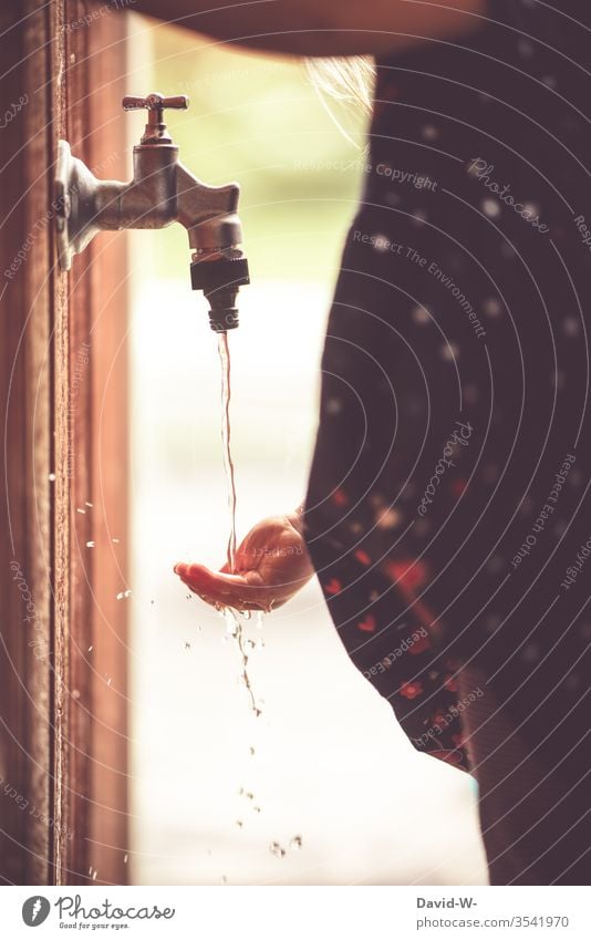 Kind fängt Wasser aus dem Wasserhahn mit der Hand auf Finger fühlen Wassertropfen neugierig sommer sommerlich draußen nass Tropfen Garten grün Sommer