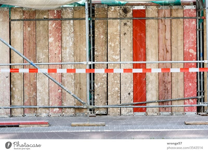 Baustellensicherung und Baugerüst auf einem Gehweg Bauzaun Baustellenzaun Rüstung Rüstbohlen Absperrband Sicherheit Schutz Außenaufnahme Farbfoto Menschenleer