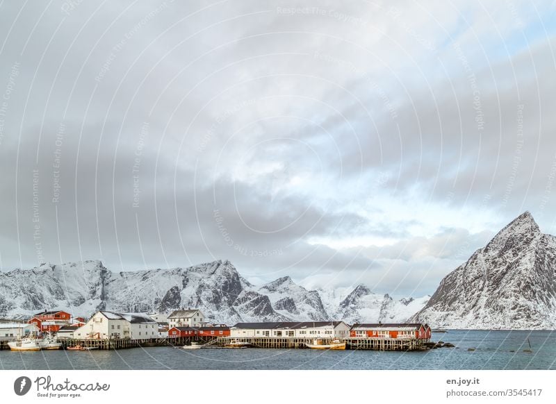 Hamnoy auf den Lofoten mit Aussicht auf die kleinen roten Häuschen die auf verschneiten Felsen stehen zur blauen Stunde Norwegen Skandinavien Hamnøy Rorbuer