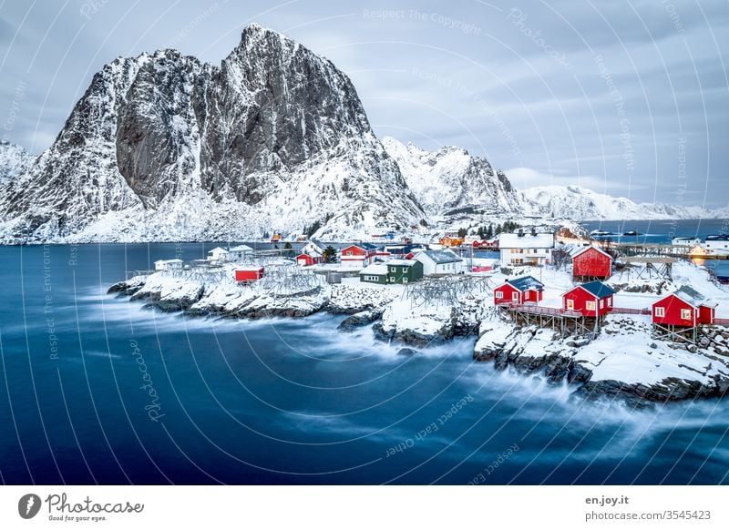 Hamnoy auf den Lofoten mit Aussicht auf die kleinen roten Häuschen die auf verschneiten Felsen stehen zur blauen Stunde Norwegen Skandinavien Hamnøy Rorbuer