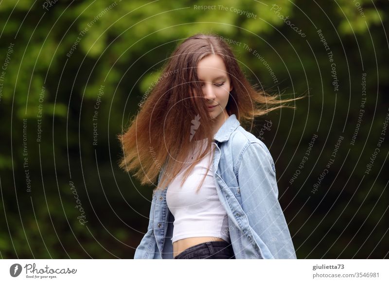 Porträt einer hübschen fröhlichen jungen Frau, Teenager mit langen Haaren, im Park Halbprofil Wegsehen Bewegungsunschärfe Schatten Licht Tag Außenaufnahme