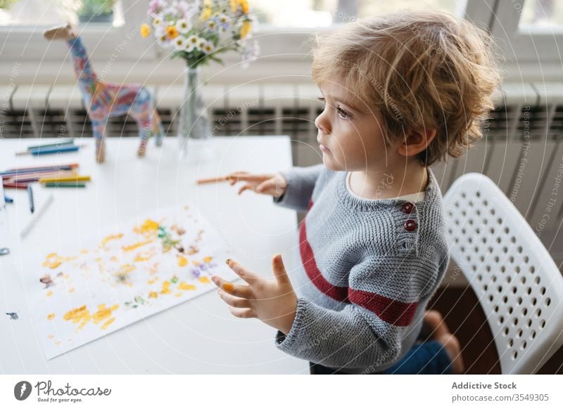 Fokussiertes blondes Kind benutzt Gouache zum Fingermalen zu Hause Junge Farbe zeichnen kreativ heimwärts Kindergarten kleben Zeichnung Papier wenig niedlich