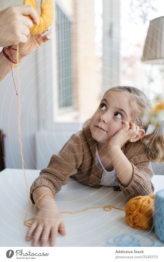 Kleine Tochter macht mit der Mutter zu Hause einen handgemachten Pompon heimwärts handgefertigt Garn Pompom kreativ Handwerk Zusammensein Bonden Mädchen Mama