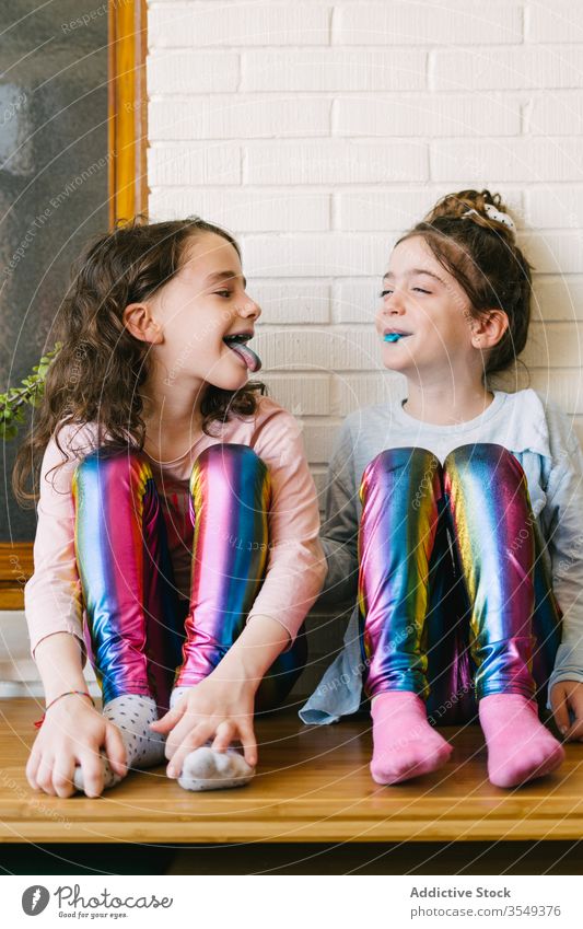 Fröhliche kleine Mädchen essen blaue Kaubonbons Kauen Bonbon Leckerbissen süß teilen heimwärts Spaß Glück Kinder geschmackvoll Lachen lecker Schwester Pyjama