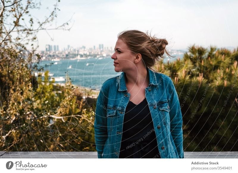 Junge Frau stellt sich gegen Grünpflanzen und Meer Ansicht Meeresufer Palast Garten Terrasse Tourist grün Baum reisen Istanbul Truthahn Himmel genießen wolkig