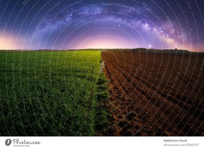 Landwirtschaftliches grünes und gepflügtes Feld Ackerbau Hälfte Nacht Milchstrasse Pflanze Boden Dämmerung Landschaft ländlich Galaxie sternenklar Bauernhof