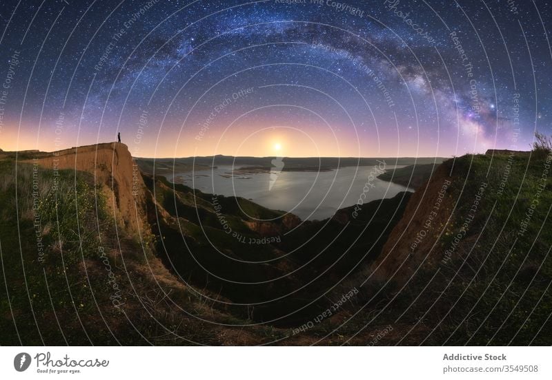 Canyon mit anonymer Person unter farbenfrohem Nachthimmel mit Milchstraße Schlucht Natur See Himmel Milchstrasse Galaxie wolkig Silhouette Wasser Formation