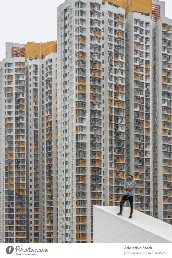 Selbstbewusster stilvoller Mann posiert auf dem Dach vor Hochhäusern in Shek Kip Mei Gebäude Hochhaus mehrstöckig wohnbedingt posierend Eigentumswohnung dicht