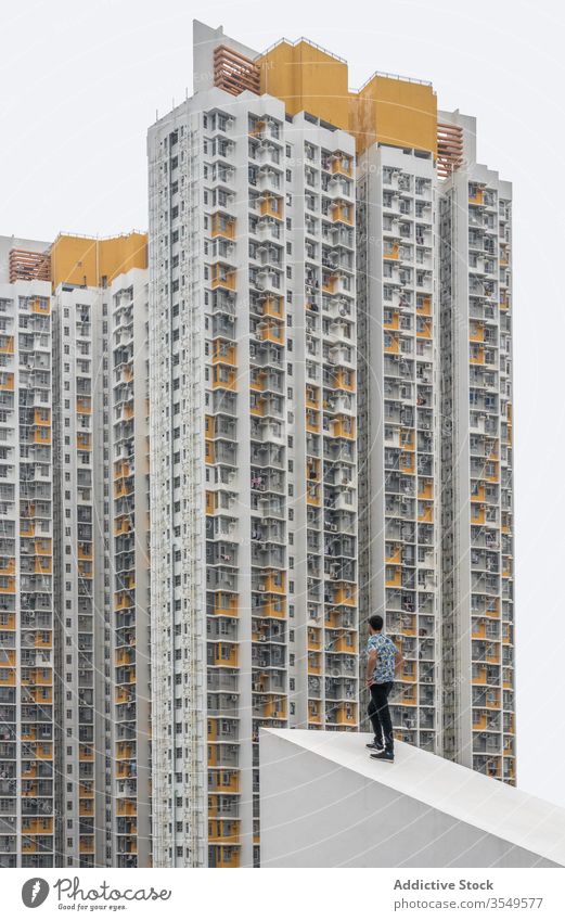 Selbstbewusster stilvoller Mann posiert auf dem Dach vor Hochhäusern in Shek Kip Mei Gebäude Hochhaus mehrstöckig wohnbedingt posierend Rücken Eigentumswohnung