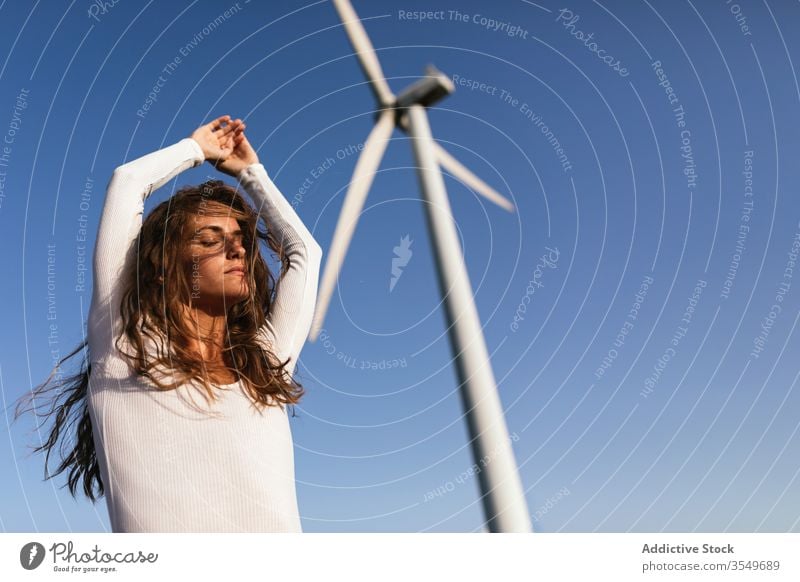 Zarte Frau tanzt allein in der Nähe des Windparks auf sonnigem Feld Tanzen Landschaft sinnlich Natur Ökologie schlank Stil hochreichen alternativ Windmühle