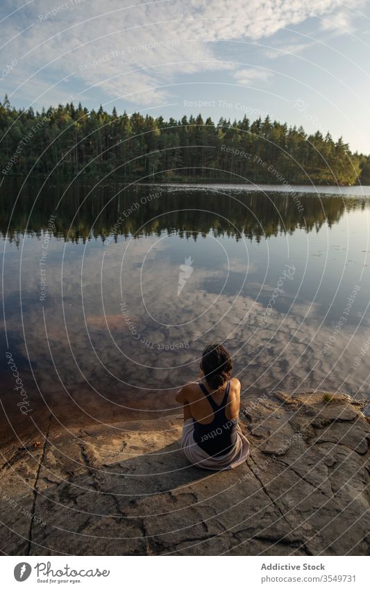 Frau im Badeanzug sitzt im Sommer am Seeufer Ufer genießen Landschaft felsig Küste Wald majestätisch ruhig Windstille Gelassenheit Harmonie friedlich idyllisch