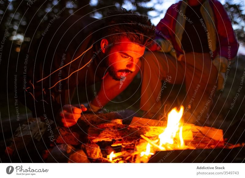 Mann mit Brennholz beim Lagerfeuermachen im Wald Wohnmobil Freudenfeuer Nacht Totholz Aufwärmen männlich Windstille Reisender ruhig Wälder genießen Wochenende