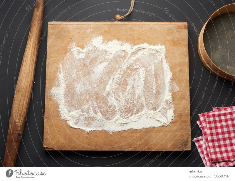 weißes Weizenmehl, das auf einen schwarzen Tisch und ein hölzernes Nudelholz gestreut wird Teigwaren Mehl Lebensmittel frisch Frische Korn heimwärts backen