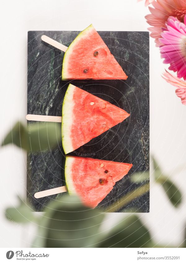 Wassermelonenscheibe Eis am Stiel auf Marmortablett Stieleis Sommer Scheiben Murmel rosa Tablett weiß hölzern Tisch frisch Snack Beeren Blumen lecker schön hell