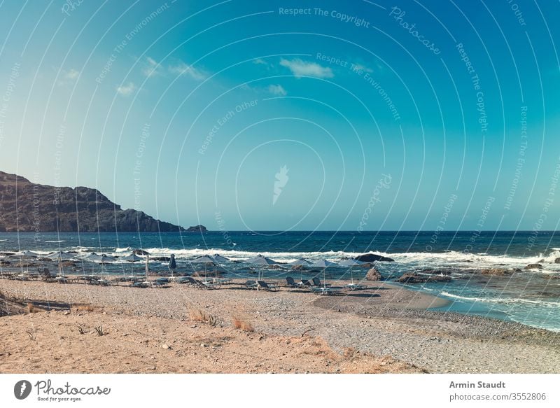 Sonnenschirme und leere Sonnenliegen an einem Steinstrand Strand Korona covid-19 Hintergrund Bucht blau Stuhl Wolkenlandschaft Küste Küstenlinie Schiffsdeck