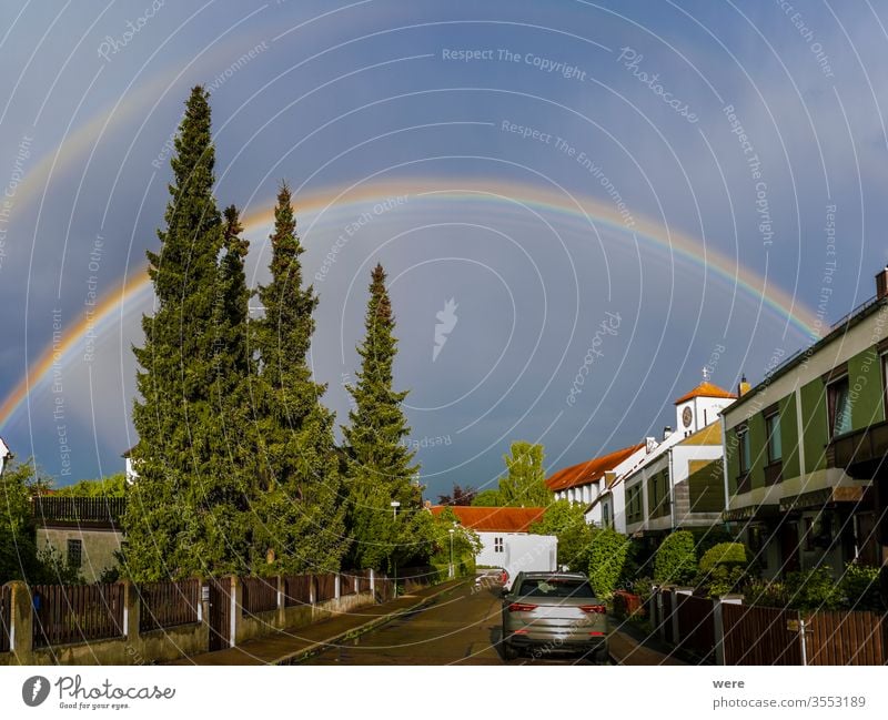 Regenbogen über einem Wohngebiet mit Kirchturm Tropfen Regentropfen Horizont Landschaft Neuanfang niemand funkeln Sonne Sonnenlicht Sonnenschein Gewitter