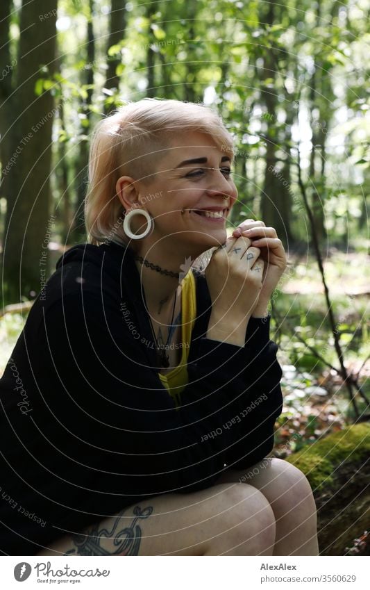 Portrait einer jungen Frau mit Piercings, Tätowierungen und Tunnel Mädchen blond Schmuck Assecoires Shirt Hemd schön draussen schauen beaobachten gelb Hand