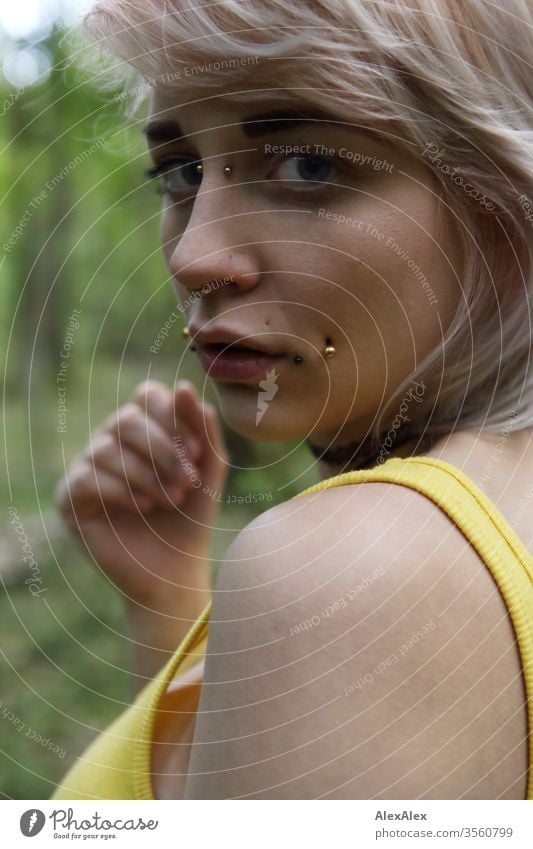 Portrait einer jungen Frau mit Piercings Mädchen blond Schmuck Assecoires Schulter Shirt Hemd schön draussen schauen beaobachten gelb Hand intensiv Erwachsene