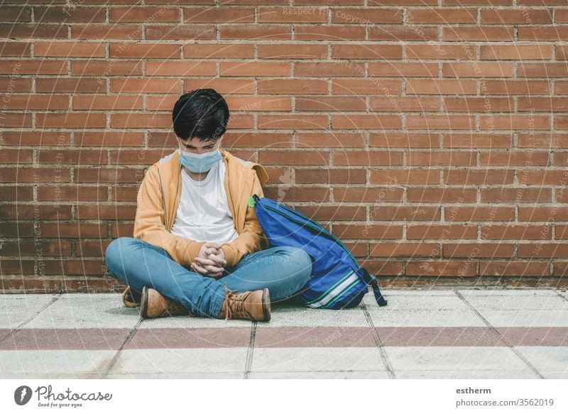 trauriges Kind mit medizinischer Maske und Rucksack Coronavirus Virus Seuche covid-19 Schule Schüler Pandemie Quarantäne Großstadt Schuljunge Traurigkeit